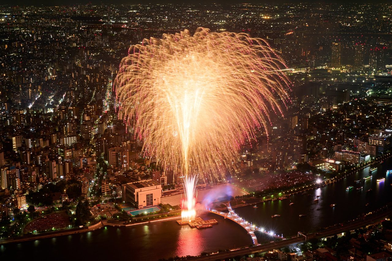 東京スカイツリー展望台の窓越しに花火を見る来場者たち