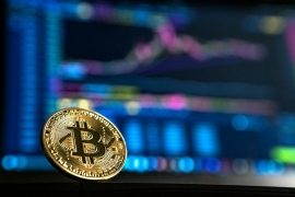 価格チャートを背景にしたビットコインコイン