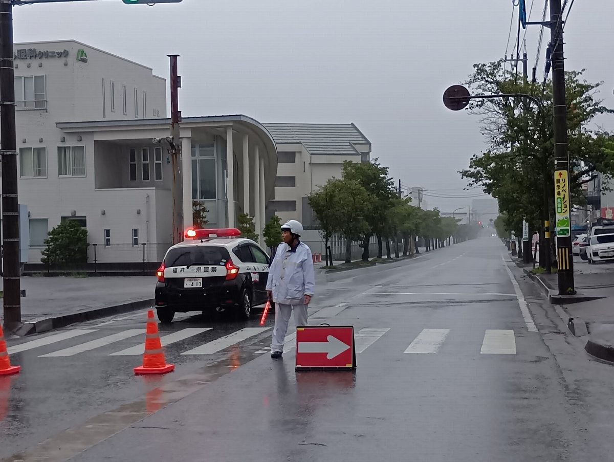 福井市内で大雨による通行止めの交通規制を行う警察官