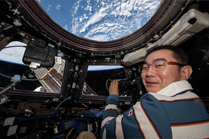 ISSのキューポラから地球を撮影する宇宙飛行士