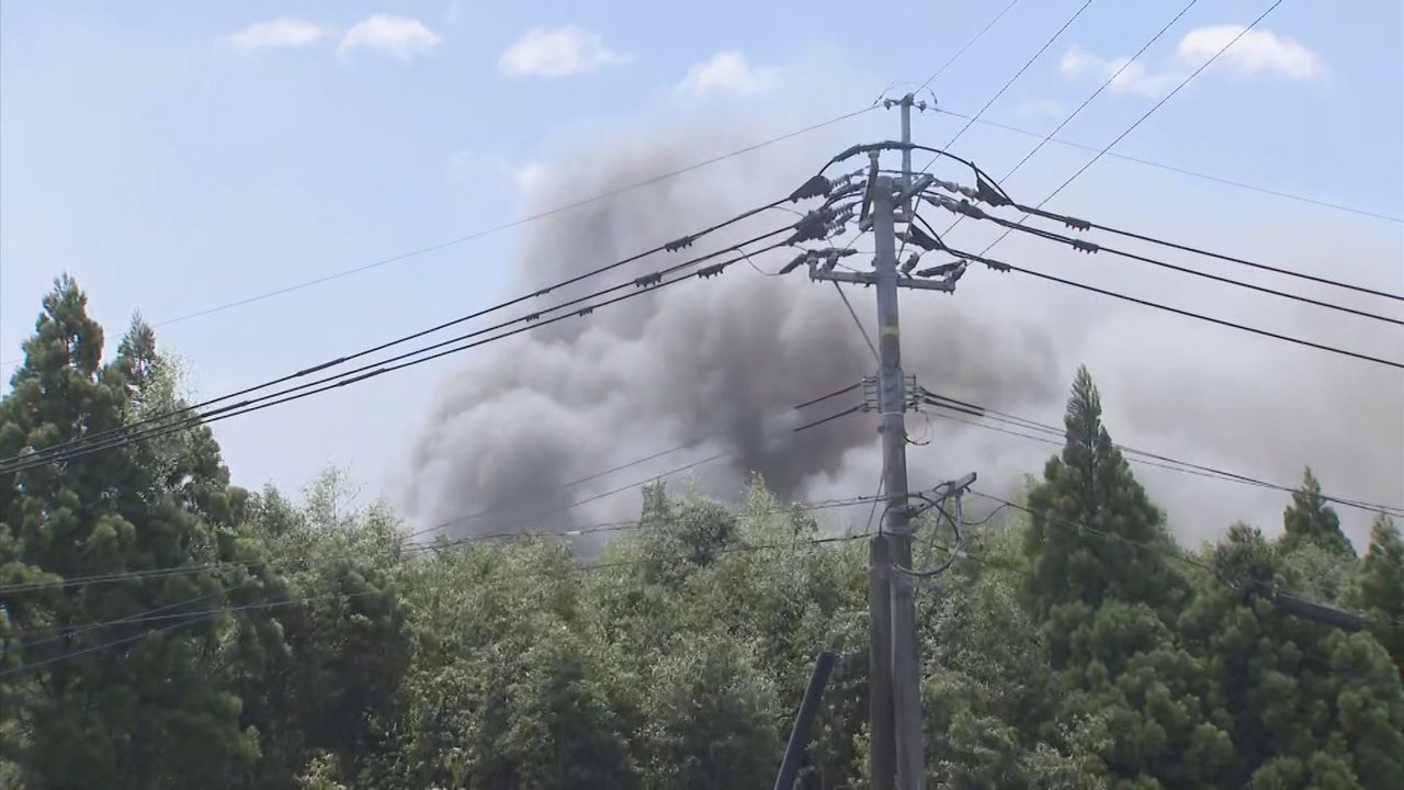 宇城市松橋町上空に広がる竹やぶ火災の黒煙、電柱と送電線越しに見える現場