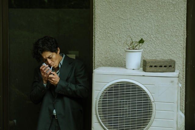煙草に火をつける矢吹恭二(小栗旬)を捉えた映画バッド・ルーテナント:トウキョウの場面写真