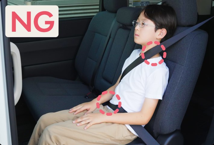 シートベルトが首と腹部にかかっているNG例。ジュニアシートを使わず座る男の子