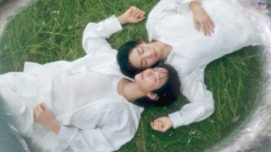 白い衣装で草の上に横たわるジョンハンとジョシュア DREAMSCAPEのコンセプトフォト