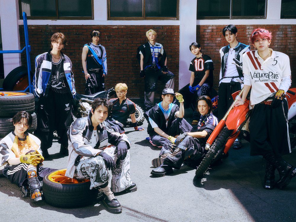 INIのアーティスト写真。バイクとタイヤのあるガレージ前に並ぶメンバー