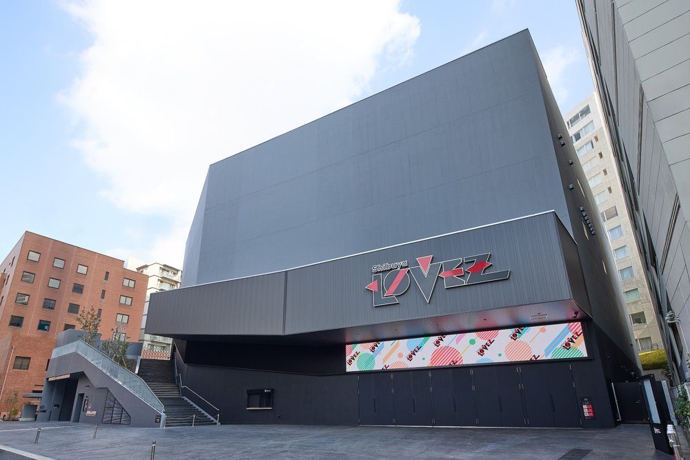 渋谷の新ホールShibuya LOVEZの外観。黒い大きな建物に赤と白のロゴと色鮮やかな幕