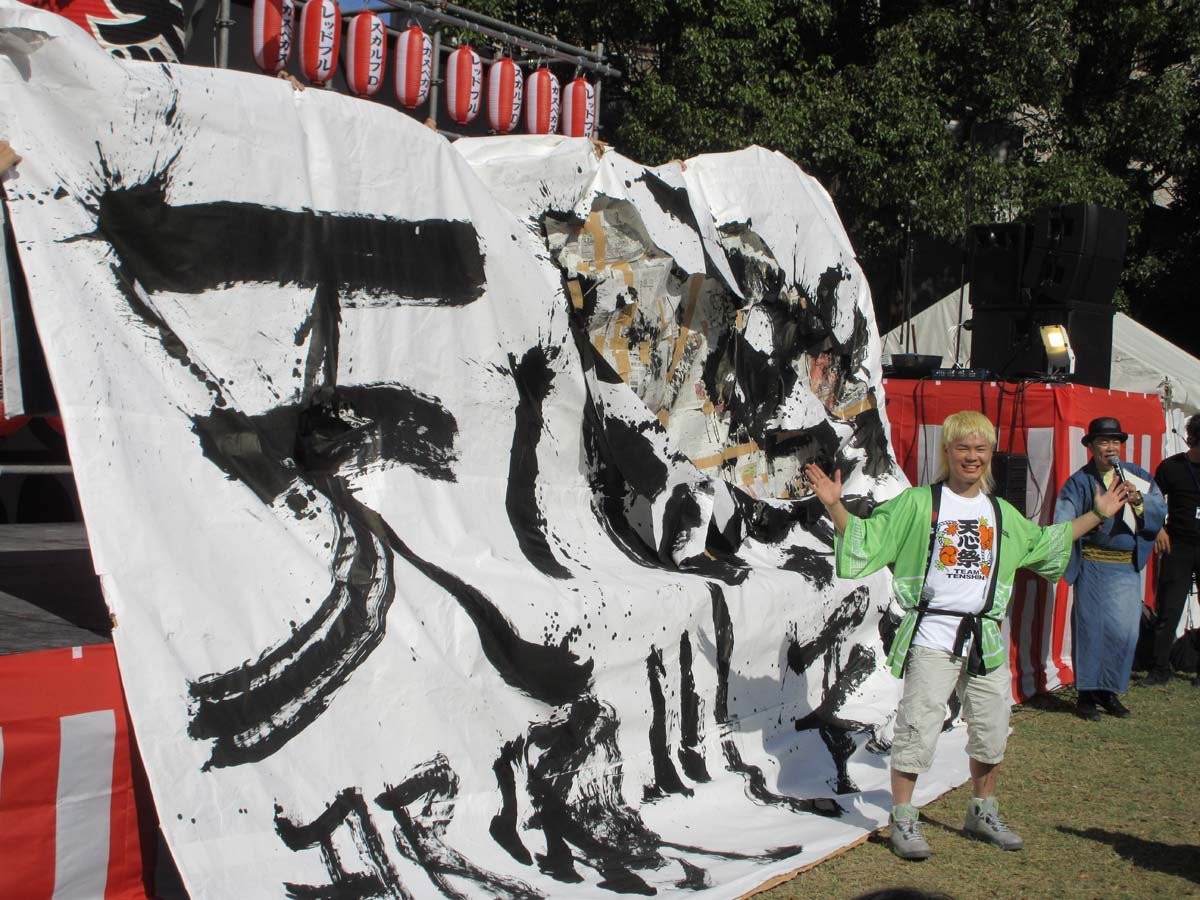 天心祭の会場で大きな書道パフォーマンスの紙の前に立つ那須川天心
