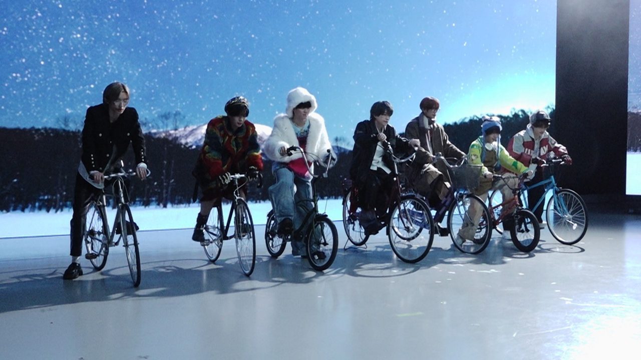 雪原の背景の前で自転車に乗るなにわ男子7人の場面カット