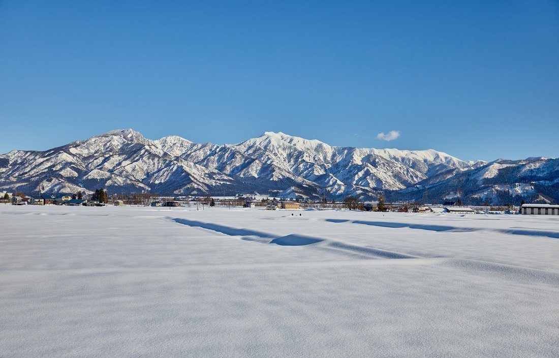 新潟県 雪に覆われた魚沼の田んぼと山並み