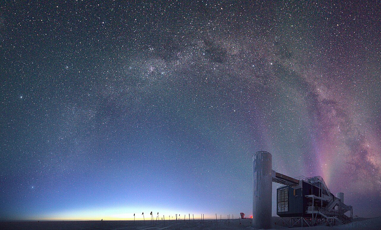 夜明けの南極点にあるアイスキューブ実験棟と天の川