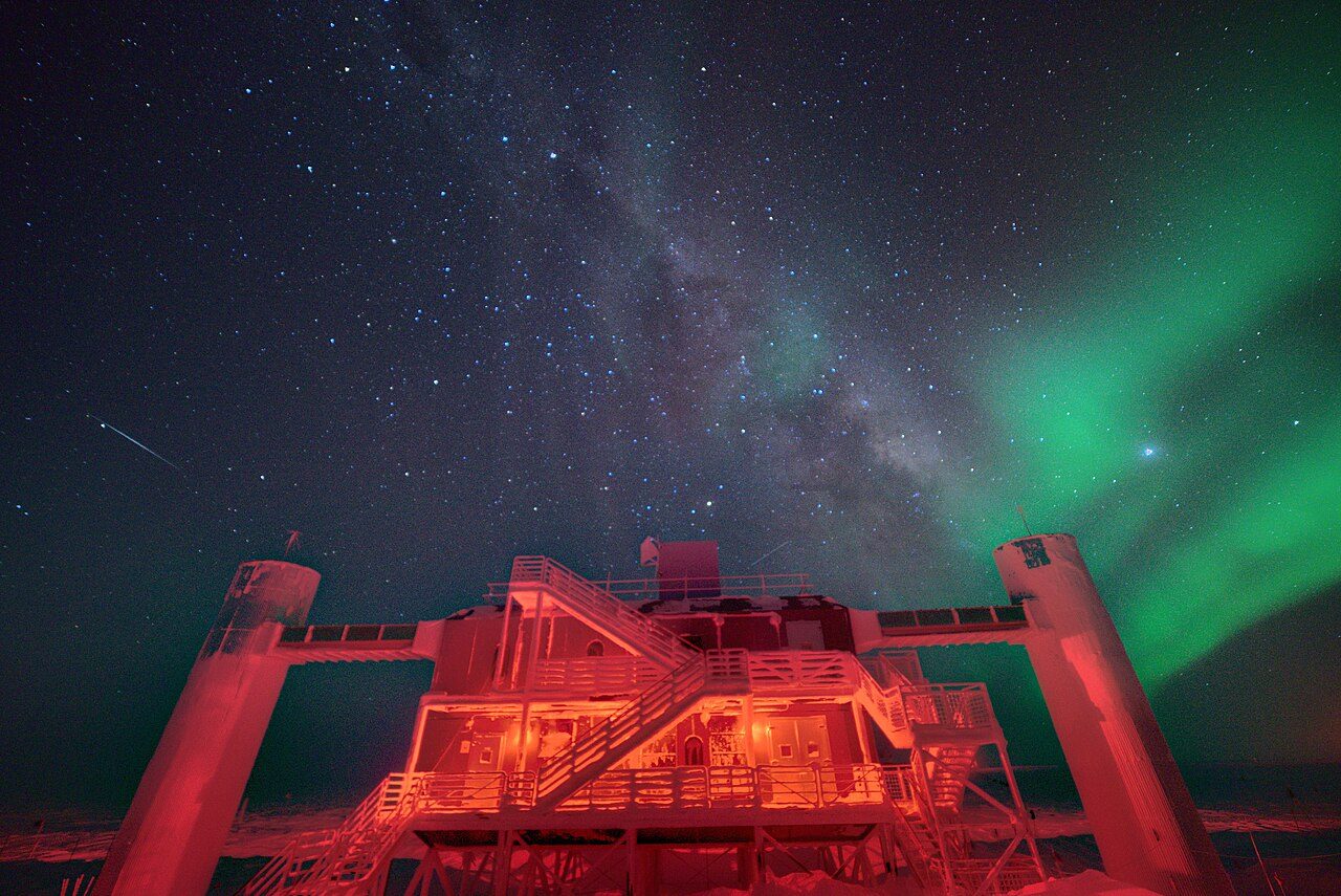夜の南極点で光るアイスキューブ実験棟と星空