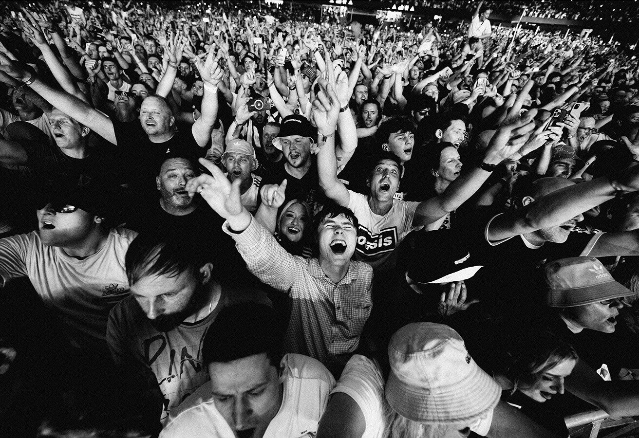 オアシスのライブで手を挙げる観客を捉えた白黒の場面写真