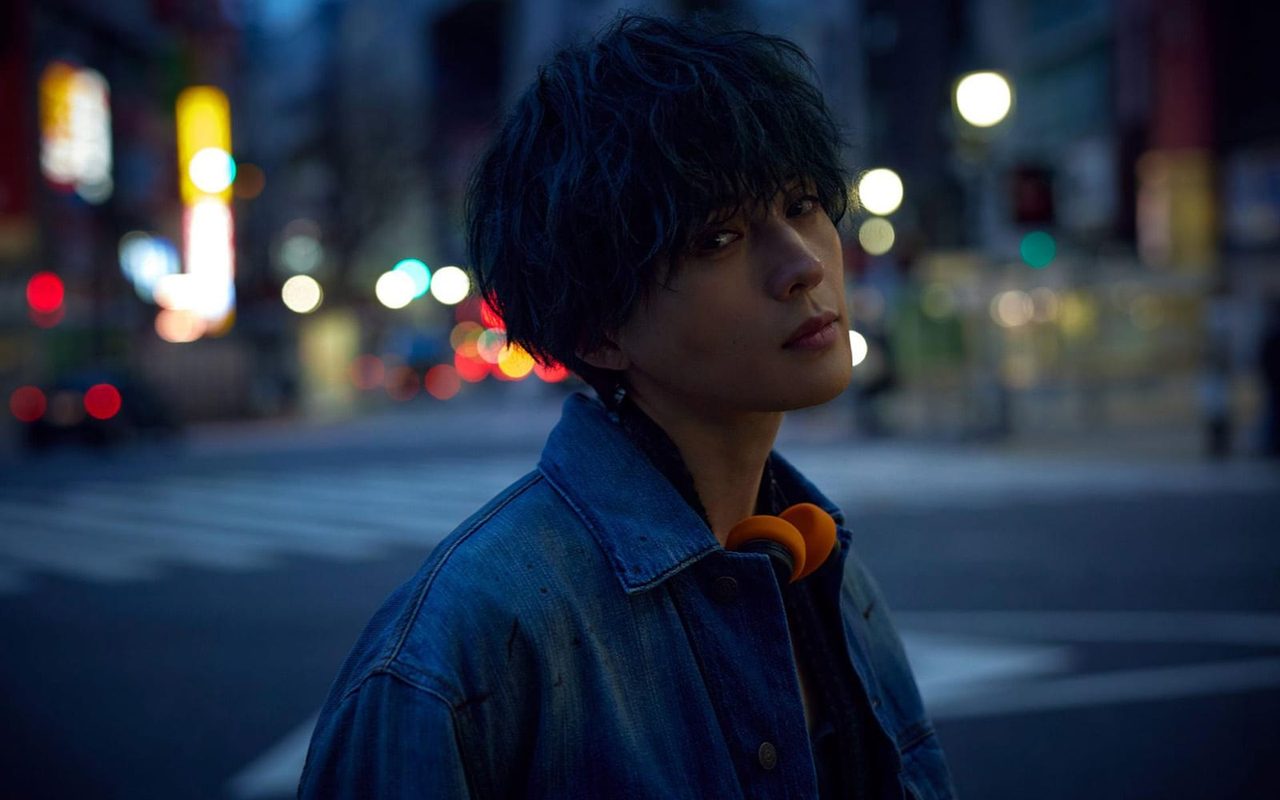 オープニングテーマ「LIKE³」を担当する八木勇征のアーティスト写真。夜の街でデニムジャケットを着ている