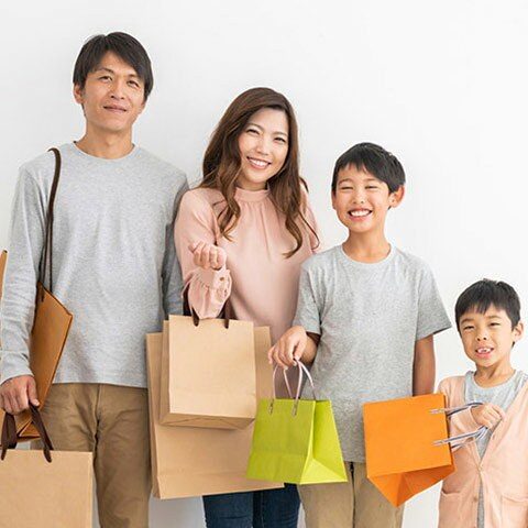 家族で買い物袋を持つ写真。楽天市場での買い回りで日用品をまとめ買いするイメージ