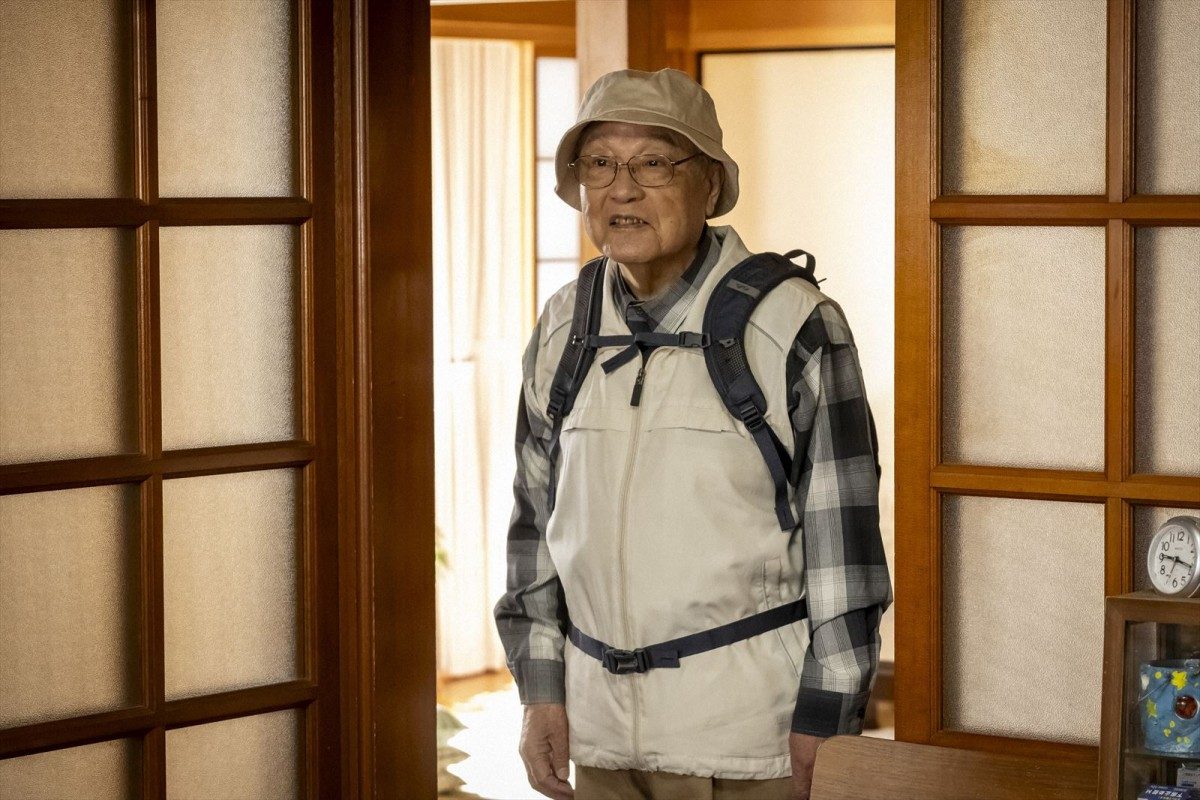 ドラマ「老害の人」の場面写真 リュックを背負い帽子をかぶった高齢男性が部屋に立つ
