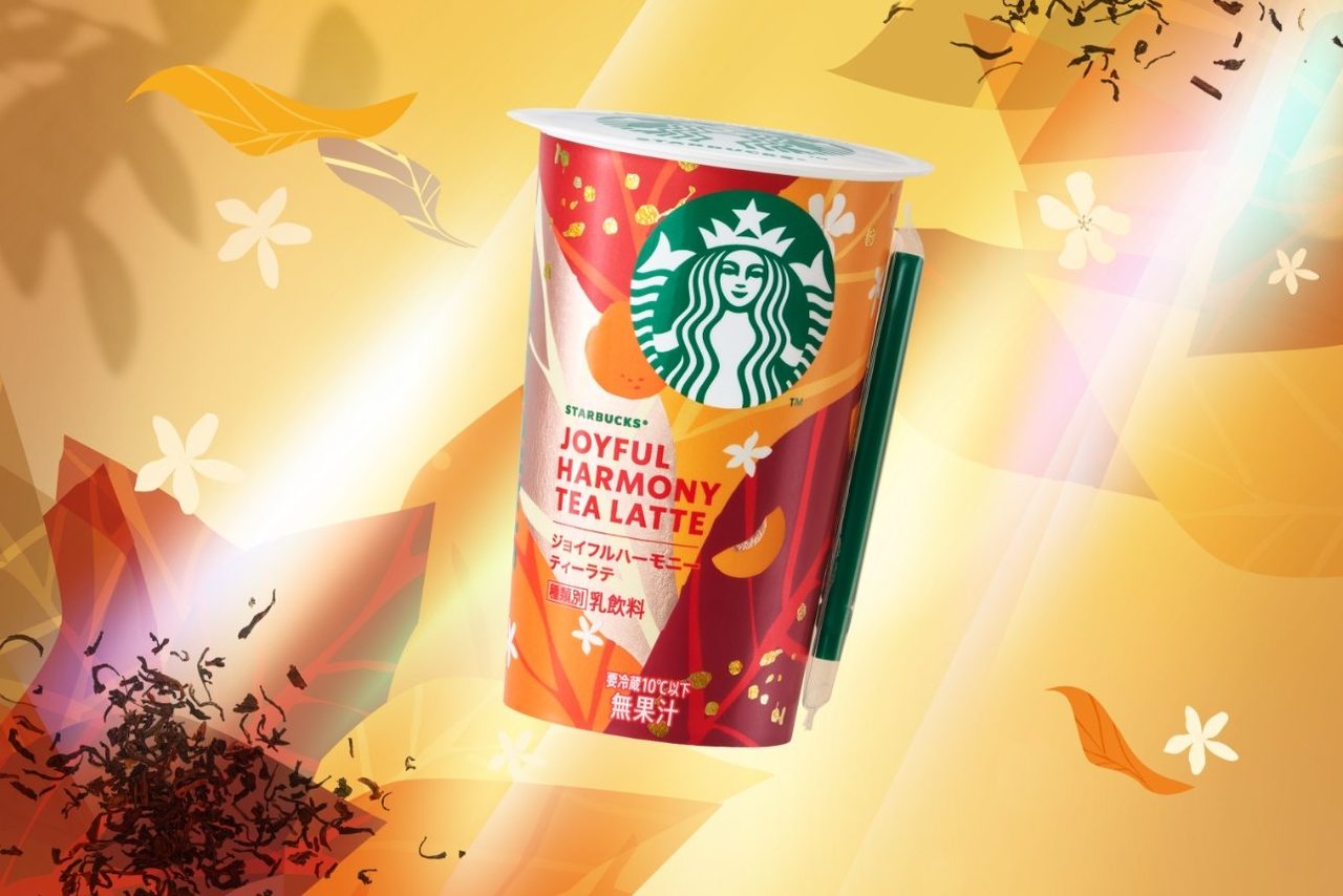 スターバックス ジョイフルハーモニーティーラテのカップとストロー。背景に白い花と茶葉
