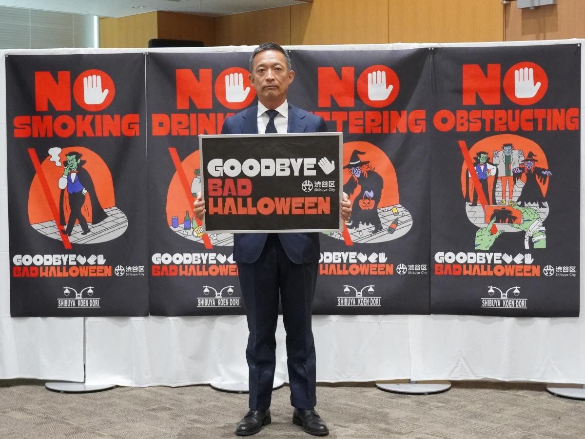 長谷部健渋谷区長がGOODBYE BAD HALLOWEENのボードを持ち、迷惑行為を禁じる4種のポスターが並ぶ会見の様子