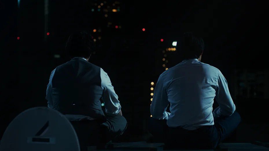 映画『九条の大罪』場面写真 ビルの屋上に並んで座る九条と烏丸の後ろ姿