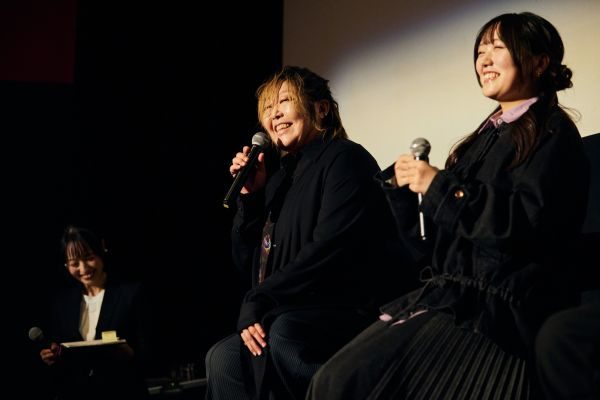 先行上映会のトークショー。緒方恵美と藤寺美徳が笑顔でマイクを持ち、左端に司会者が座っている