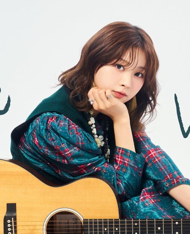 ギターを抱えて座る富田鈴花さん
