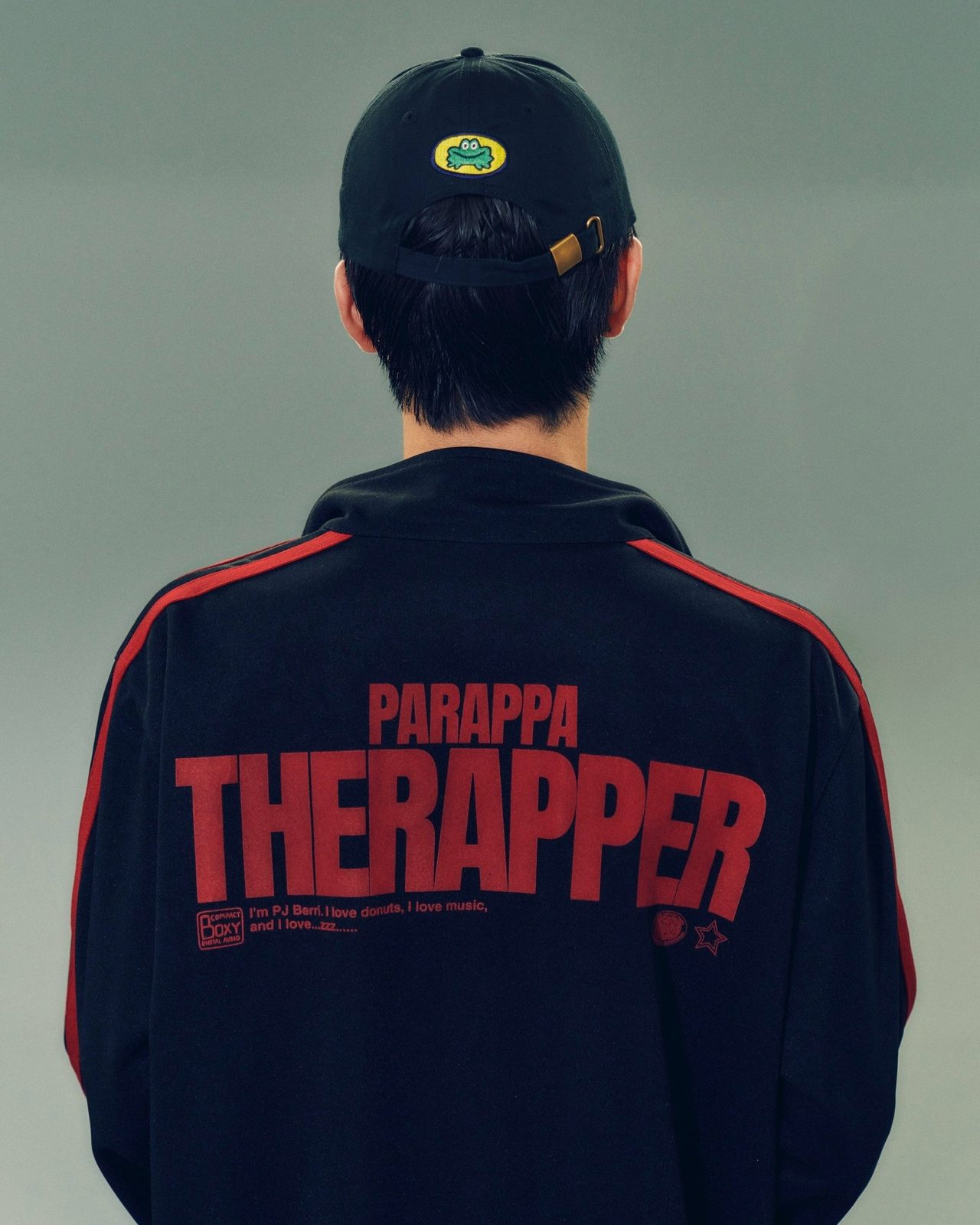 紺のトラックジャケットの背面に赤いPARAPPA THE RAPPERのロゴが入ったルック
