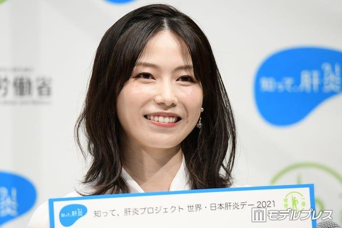 厚生労働省の肝炎啓発イベントで微笑む横山由依さん ボードを手に持った写真