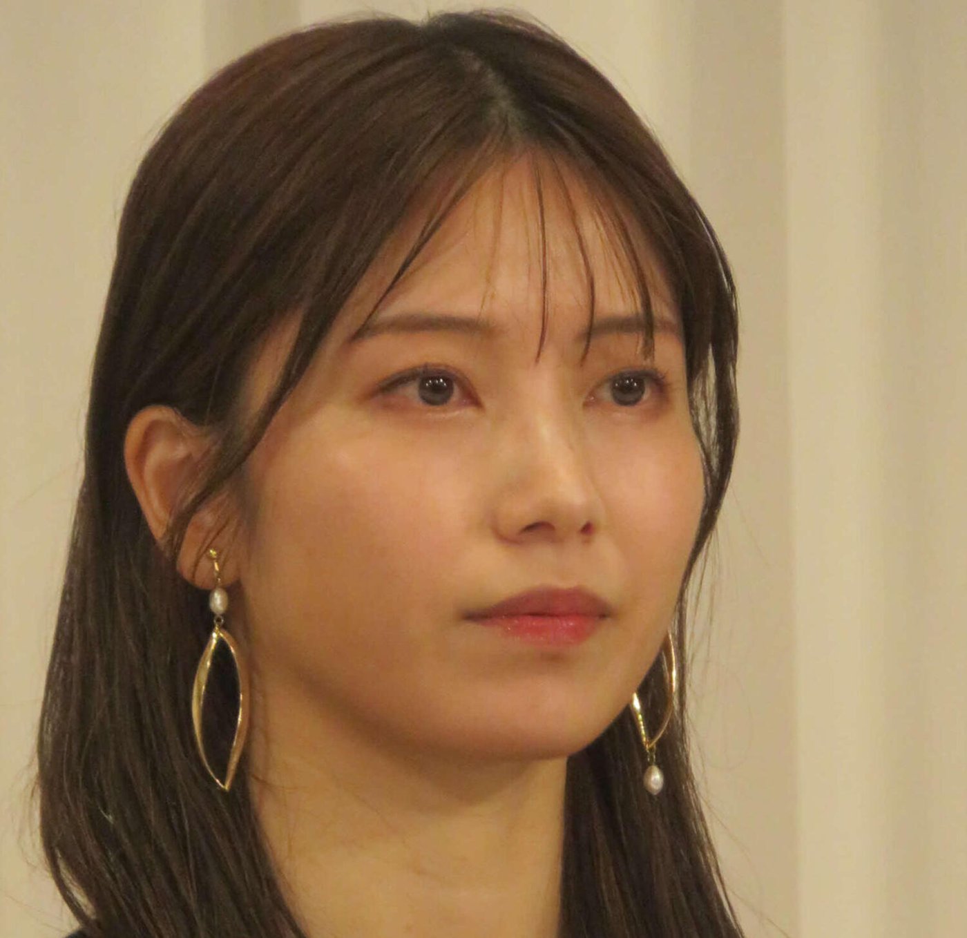 報道陣の前で神妙な表情を見せる横山由依さんのアップ写真 ゴールドのイヤリング姿